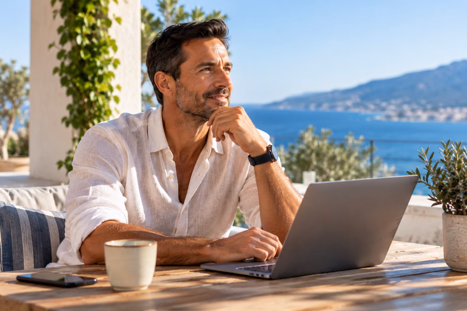 Man working on a laptop on a sea-view terrace.