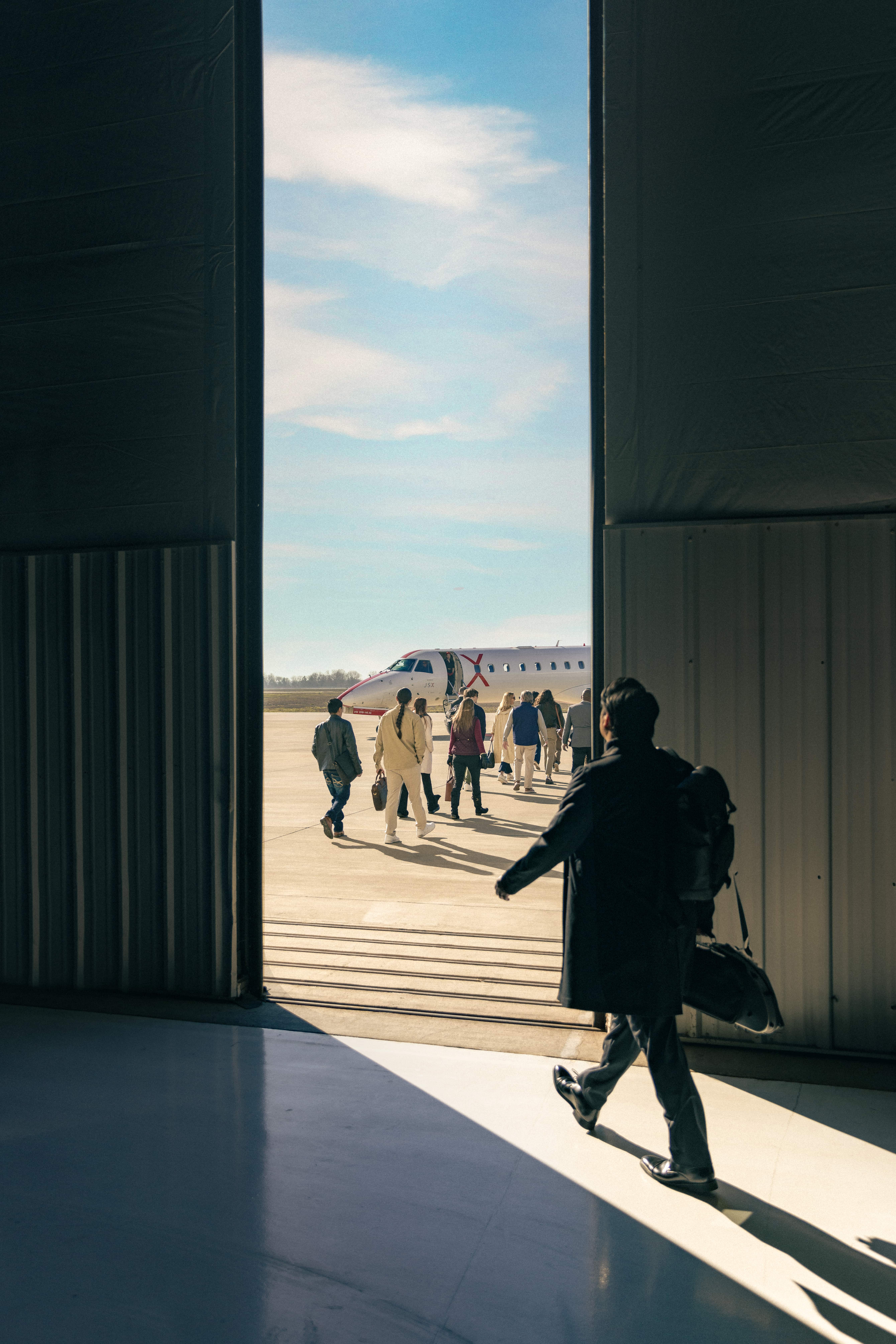 Traveler walking through a hangar door toward the tarmac