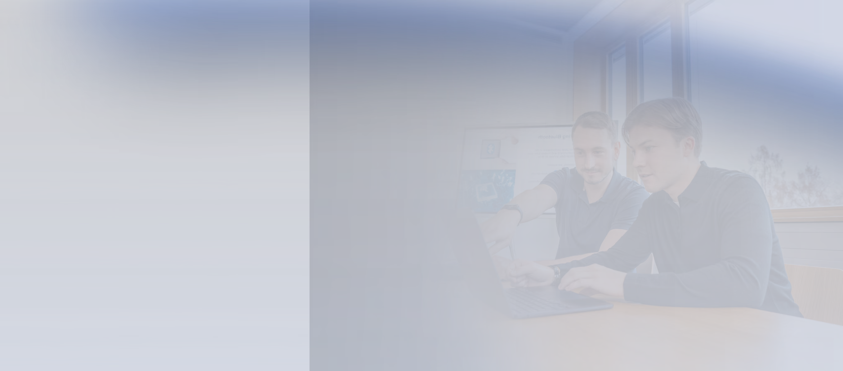 Faded photo of two engineers working together on a laptop