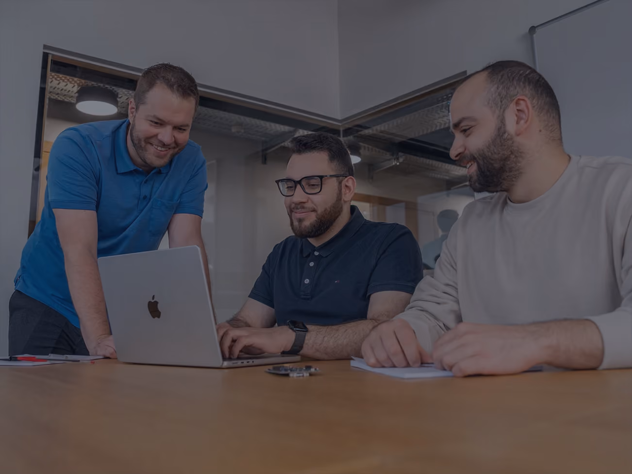 Three Dewine Labs engineers reviewing work together on a laptop