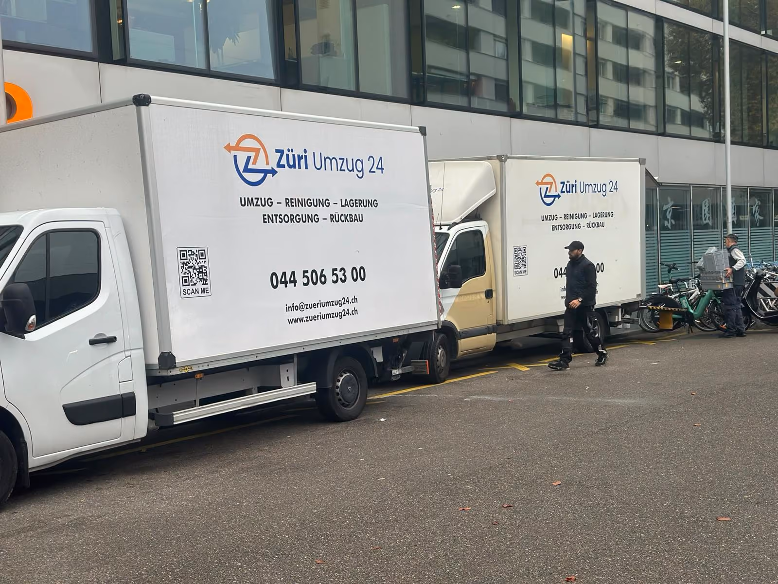Zwei Zügelwagen von Züri Umzug 24 vor einem Bürogebäude bei einem Firmenumzug