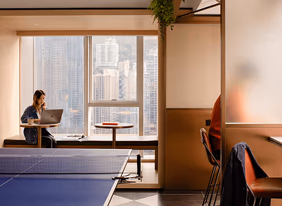 An office with skyscrapers outside the window and a table tennis table in the foreground