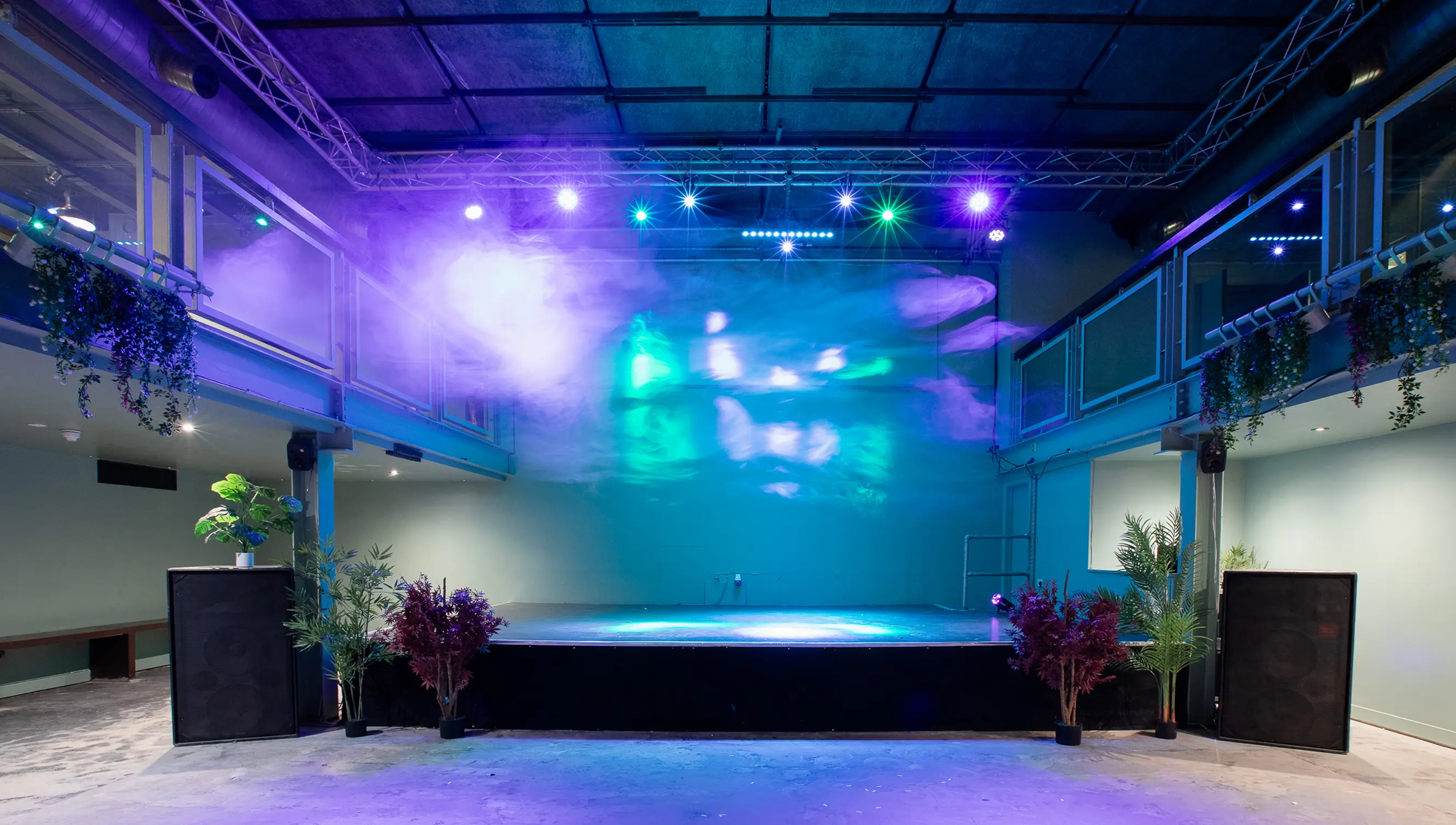 Empty Acres stage with purple and blue lighting and plants at either side.