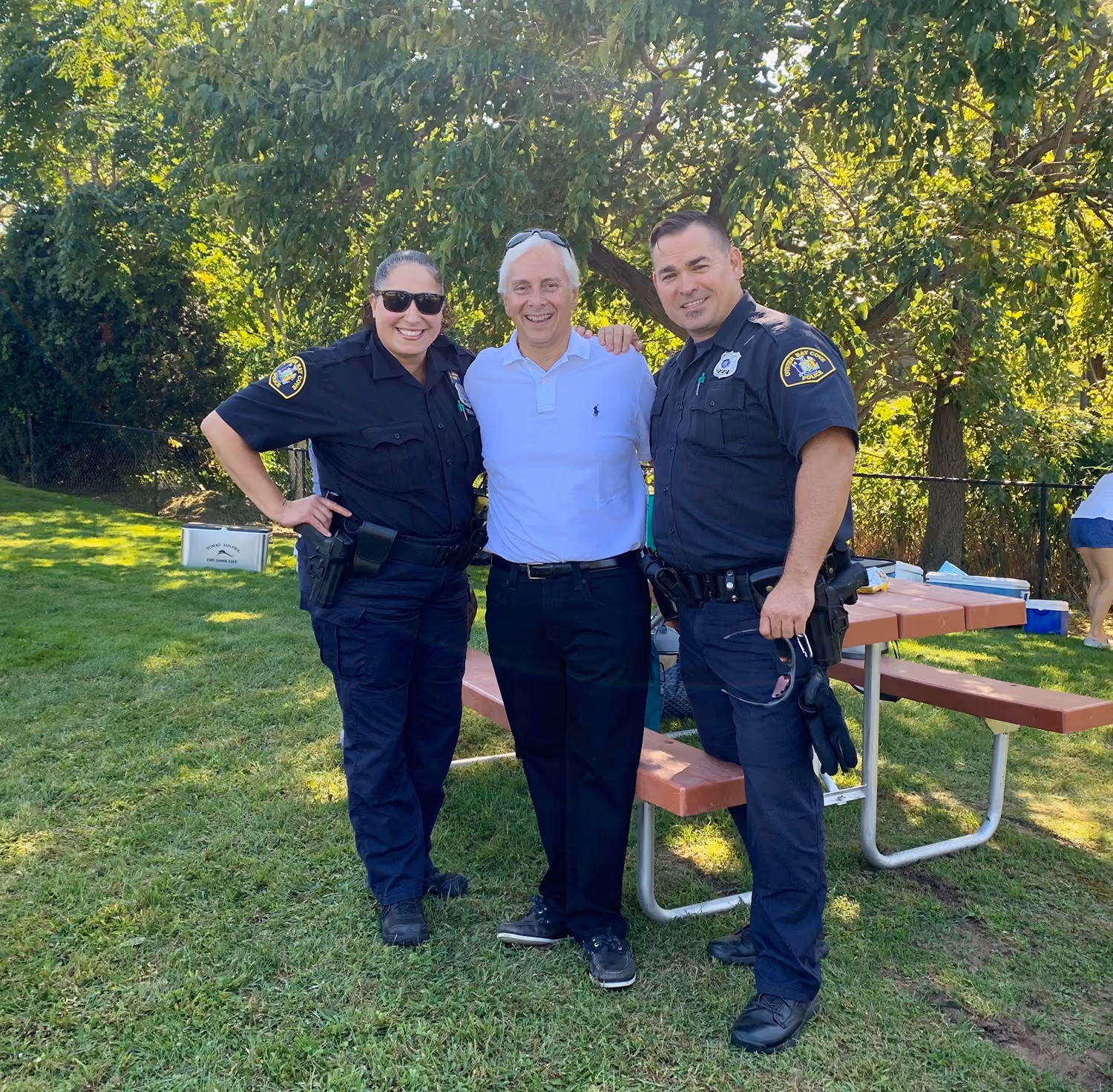Two Oyster Bay Cove police officers with a resident at a community picnic