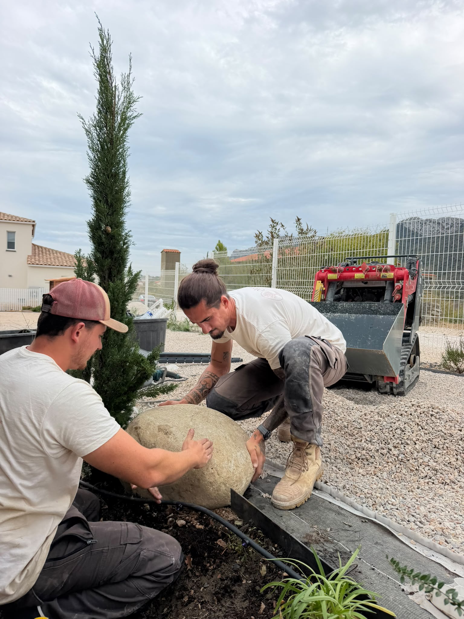 Mise en place d’une pierre et d’un cyprès sur un chantier de jardin