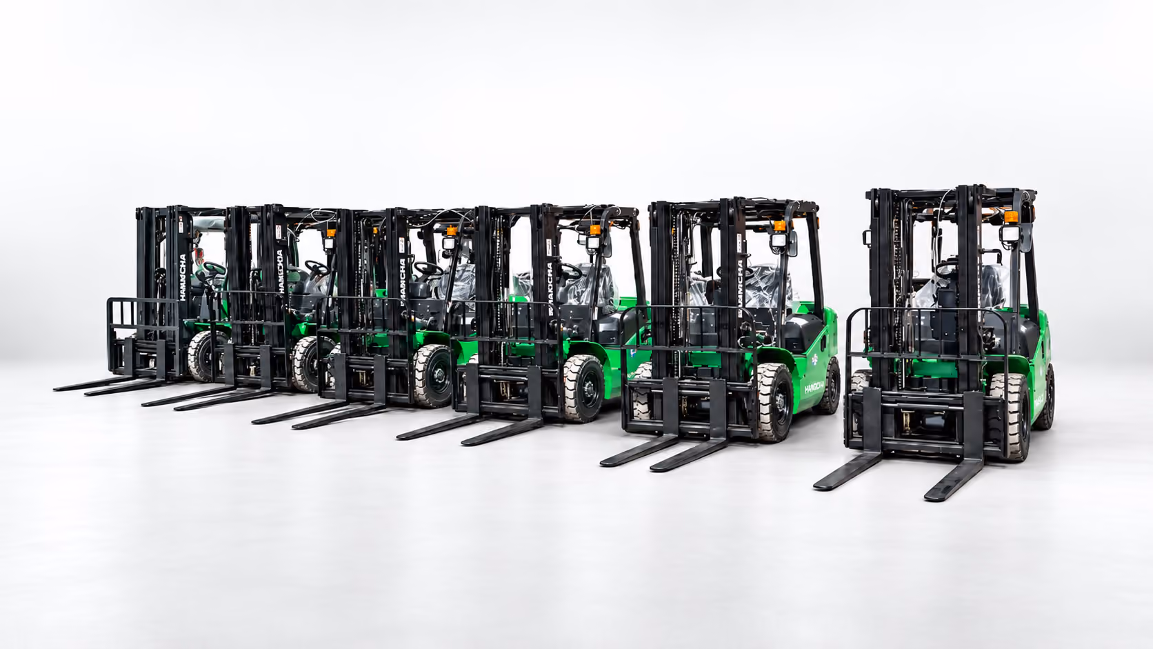 Seven green and black forklifts lined up in a row on a smooth white surface with a white background.