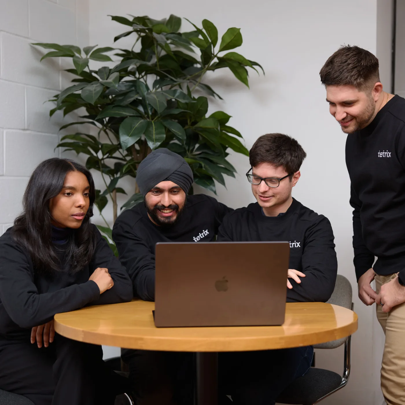 Four Tetrix team members gathered around a laptop