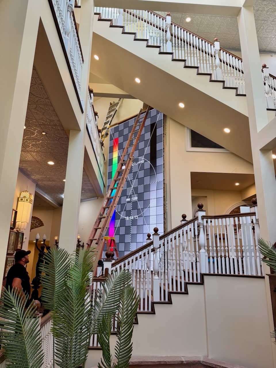 LED wall showing a test pattern with a tall ladder in front of it
