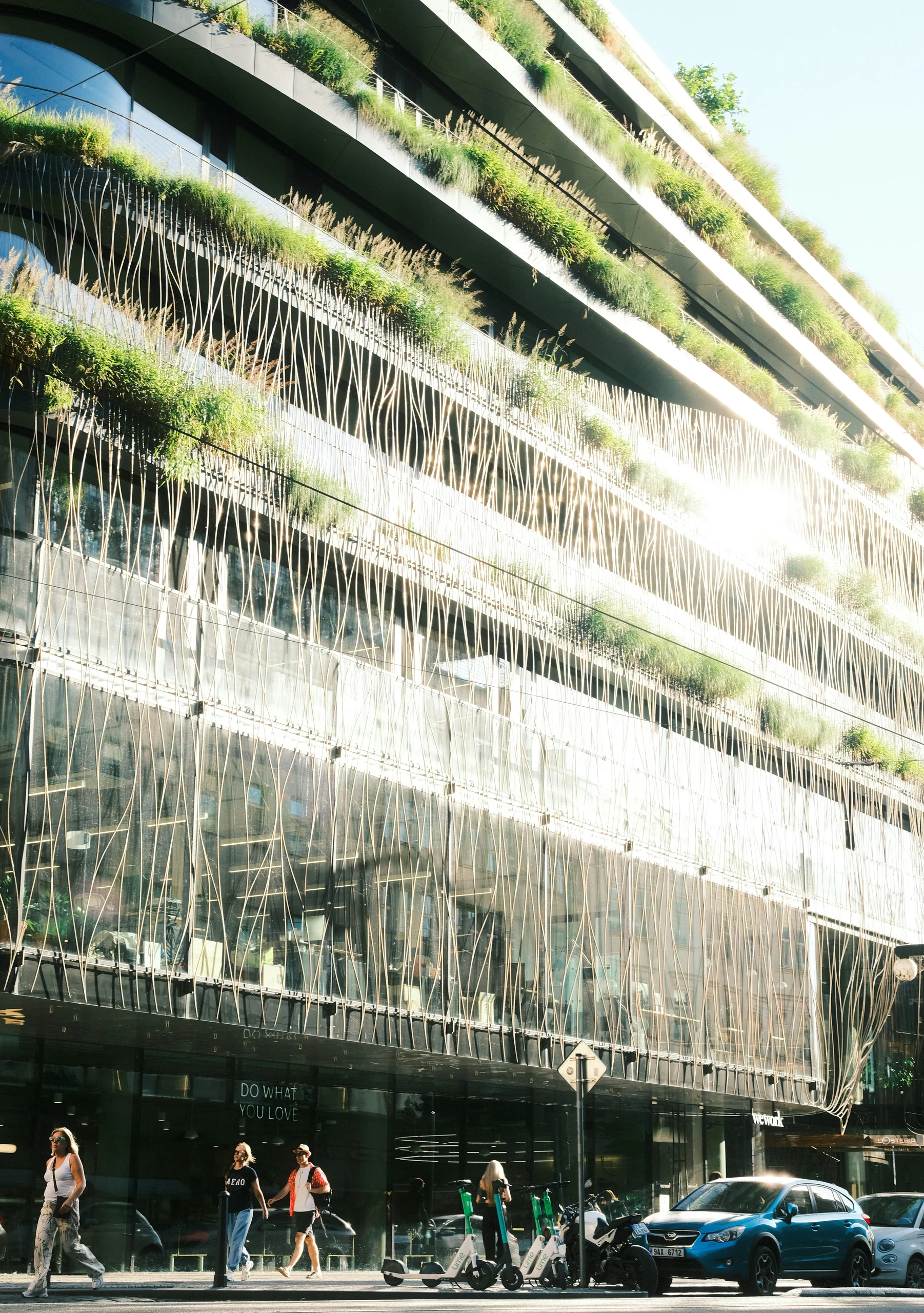 Terrassenförmige Bürofassade mit Fassadenbegrünung und organischen Streben – modernes Green‑Building.