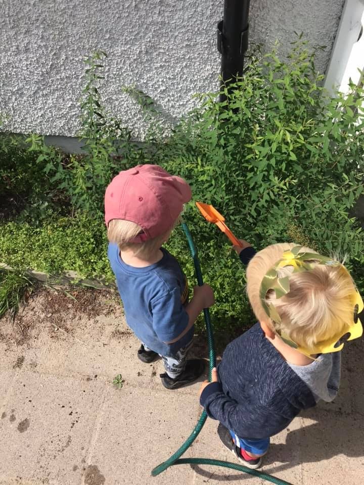 Två barn vattnar buskarna vid förskolan tillsammans