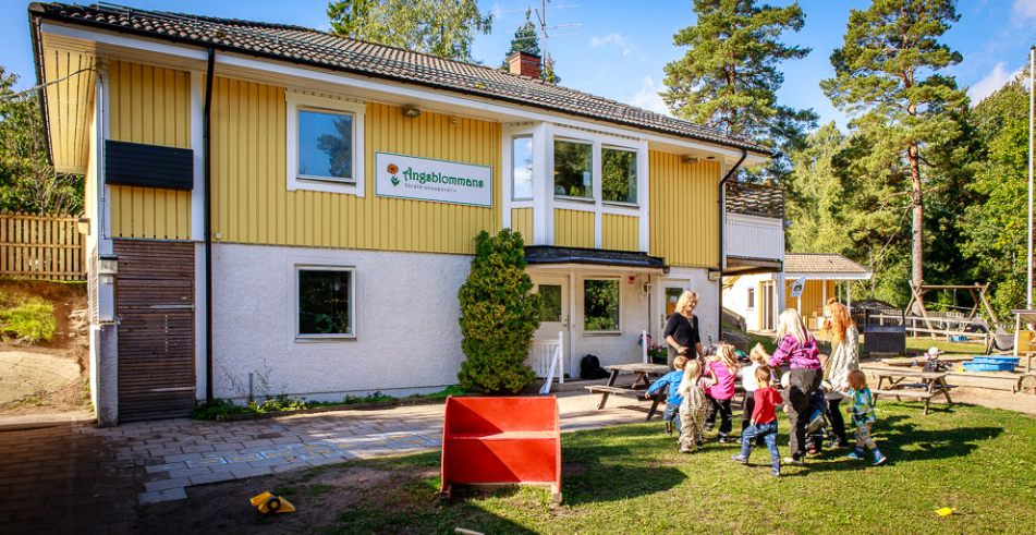 Ängsblommans gula villa med barn och pedagoger som leker på gården