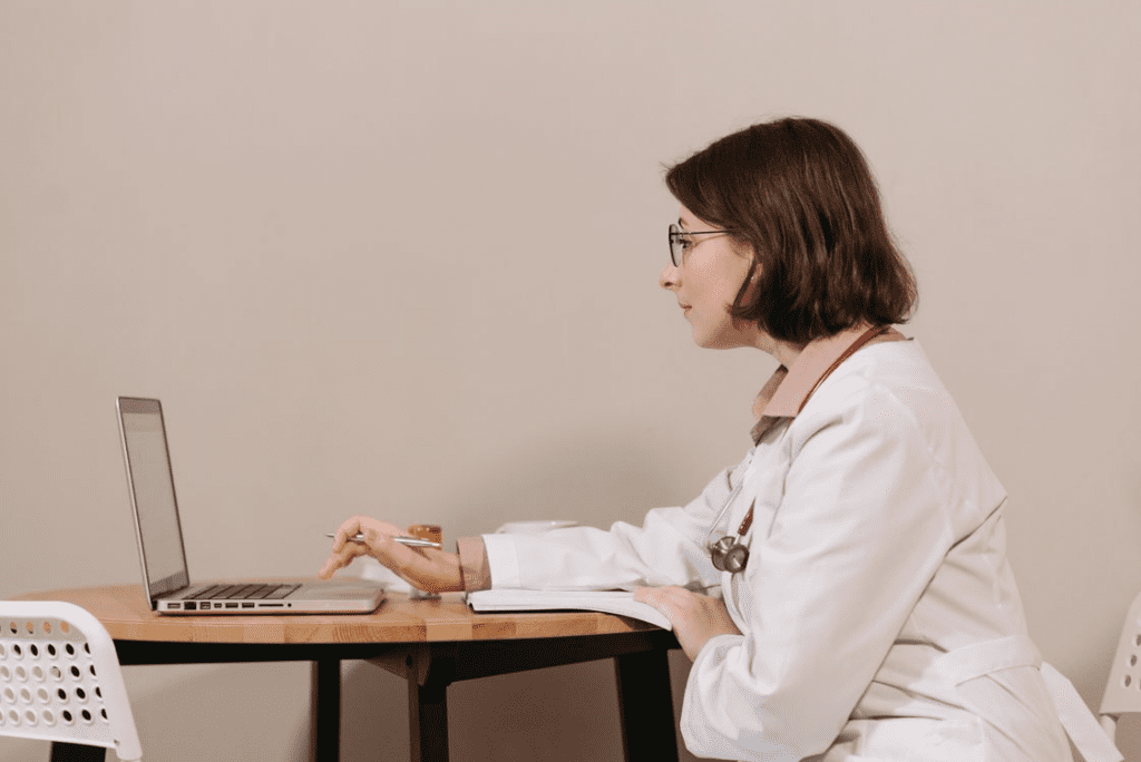 woman in white scrub using laptop