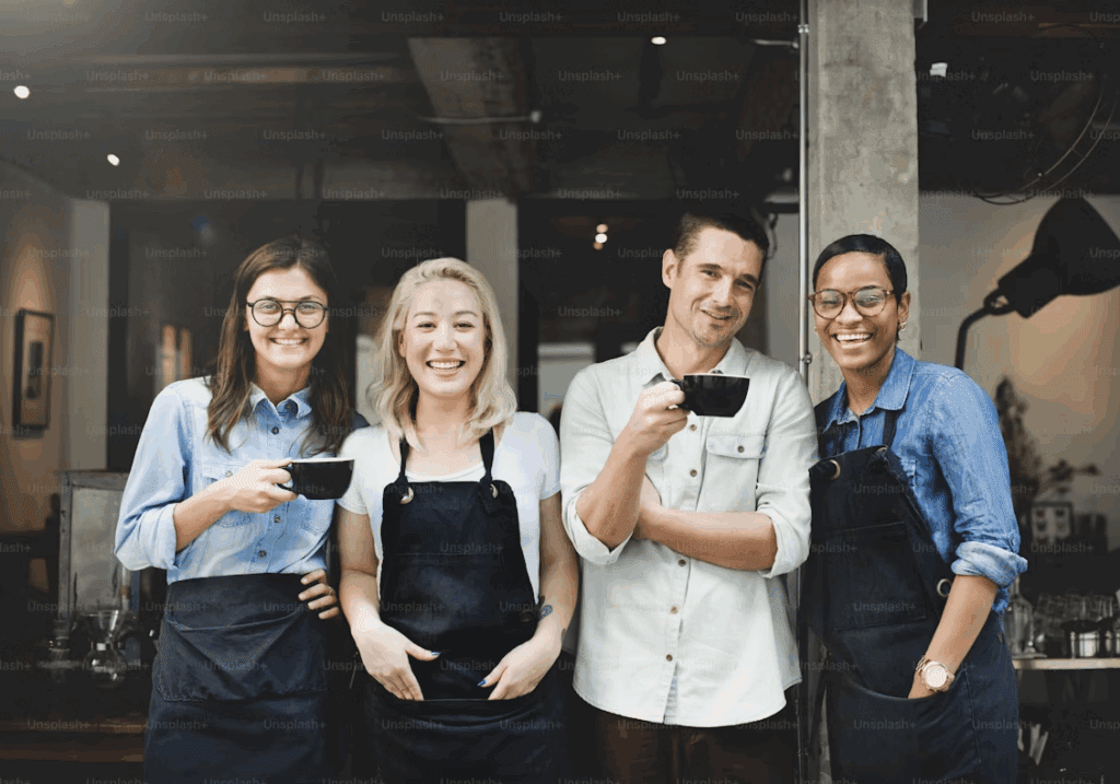 Two baristas in a coffee shop smiling and working together behind the counter.