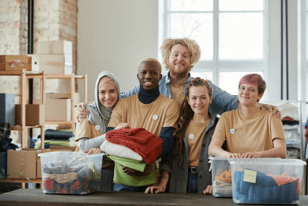 a group of volunteers sorting clothes into containers posing together