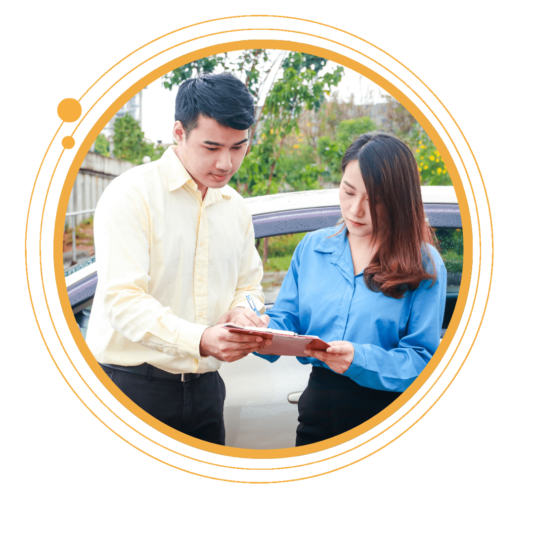 Insurance agent and customer completing a claim form beside a car