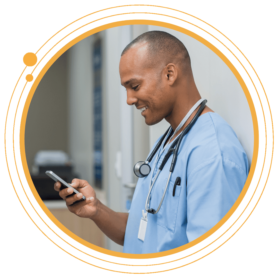 Caregiver in scrubs smiling at his phone