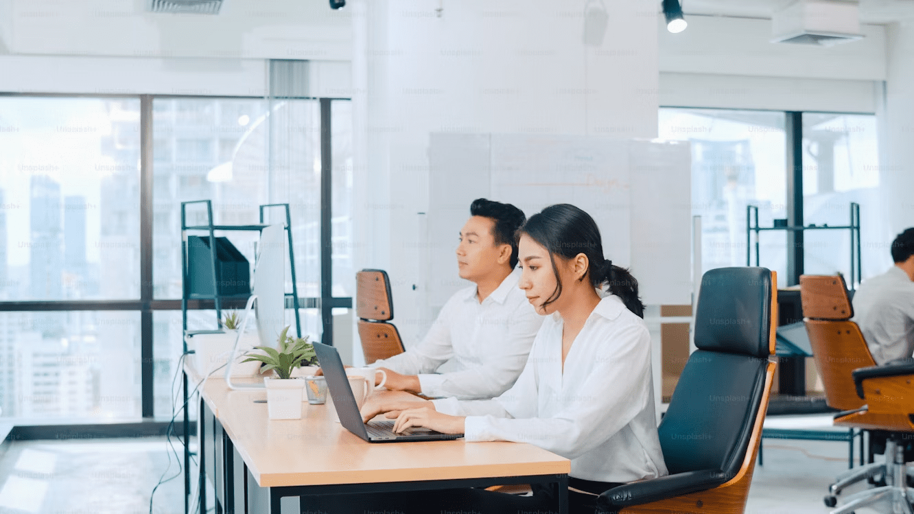 Young Asian businesswoman in smart casual attire watching a creative ideas tutorial on her laptop in a modern office setting.