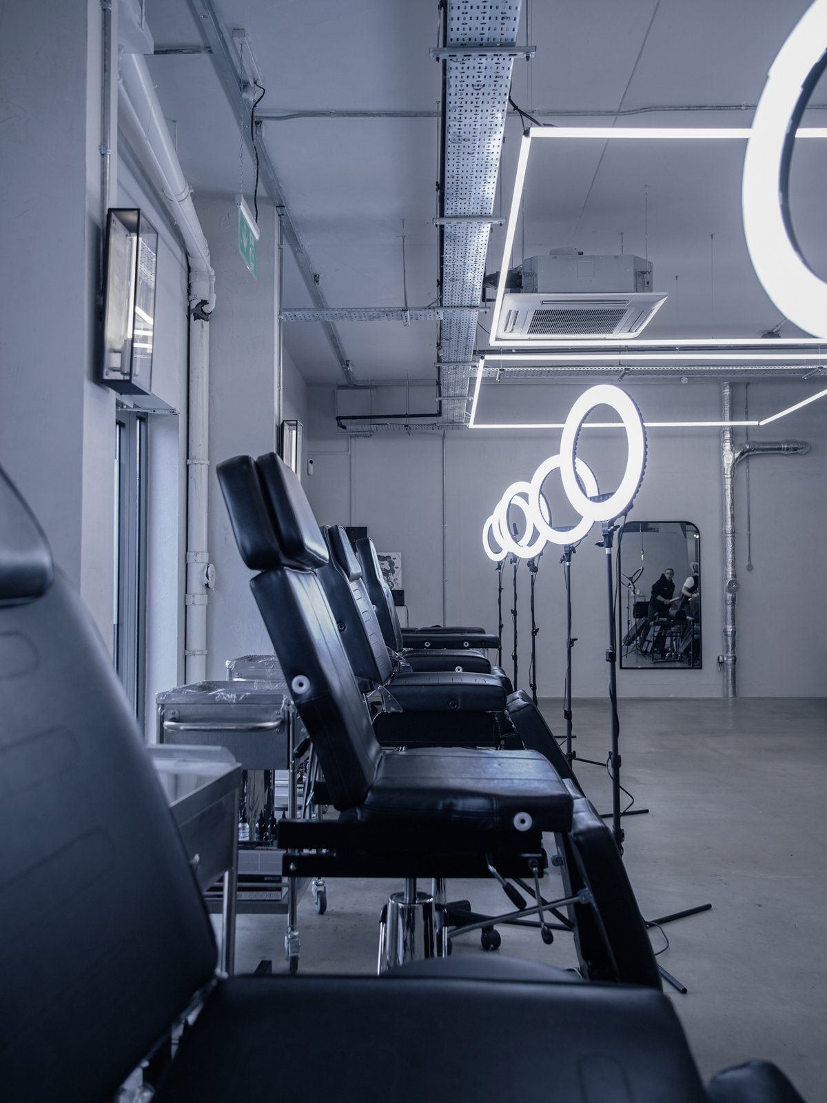 A row of tattoo chairs under ring lights