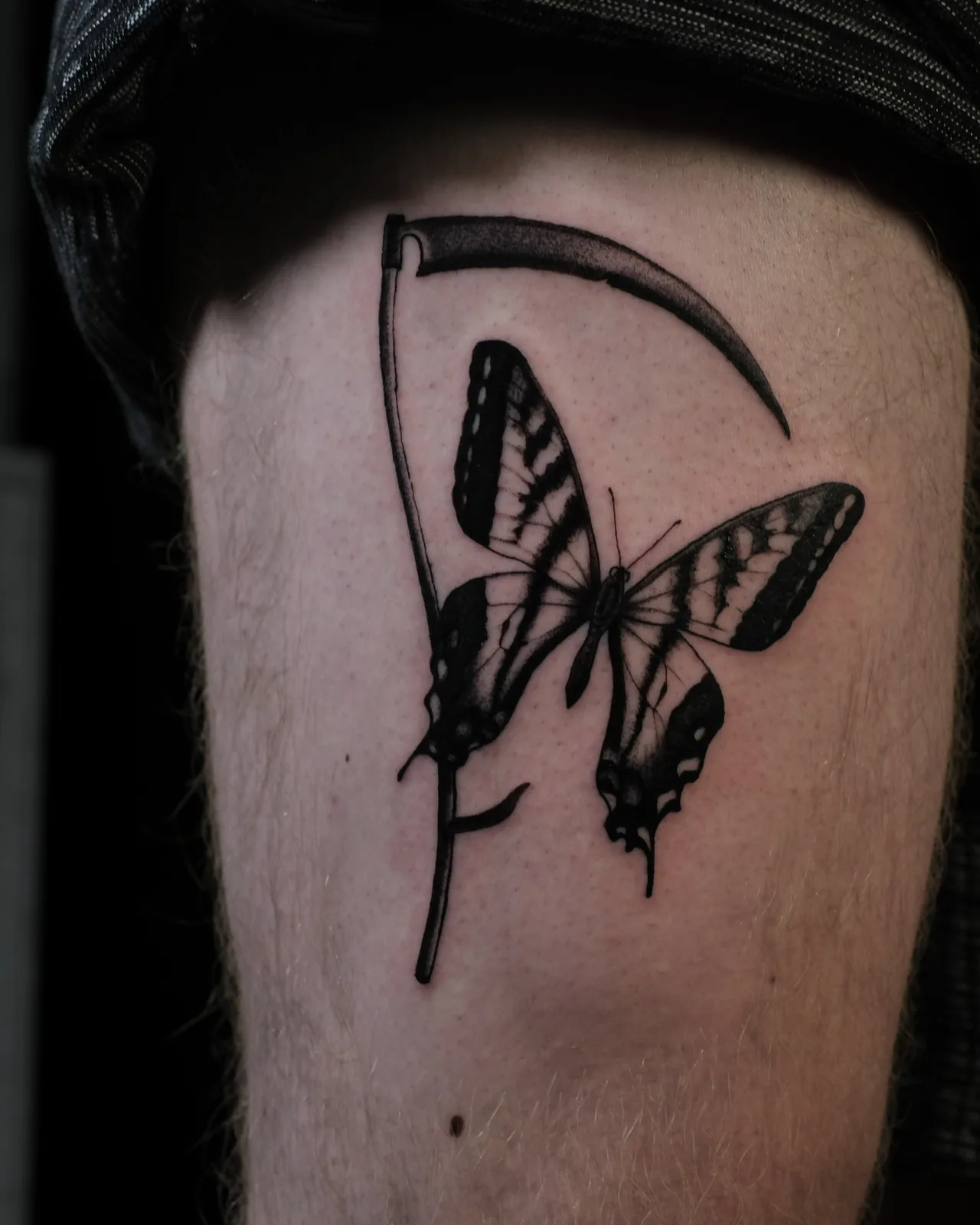 Scythe and butterfly tattoo on the thigh by Dominic Forrest at SANS PATRIE/ STUDIO