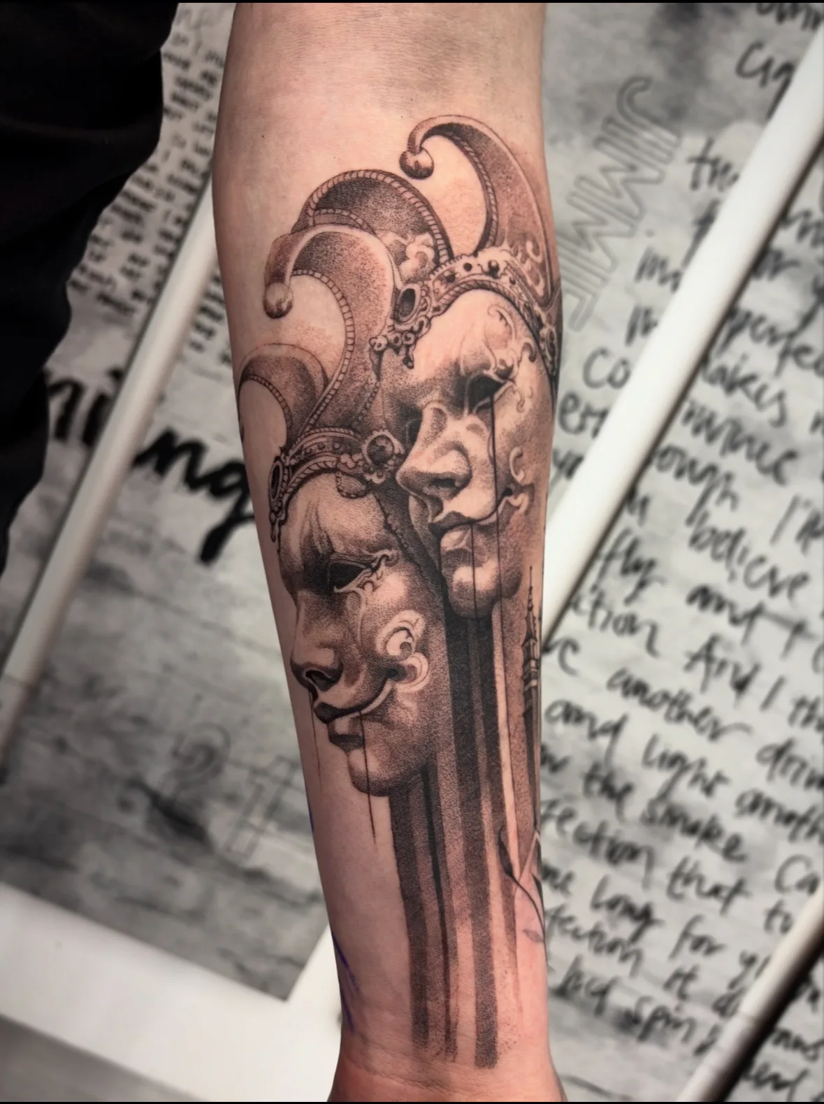Black and grey theatre masks tattoo on the forearm by Livi Muir at SANS PATRIE/ STUDIO