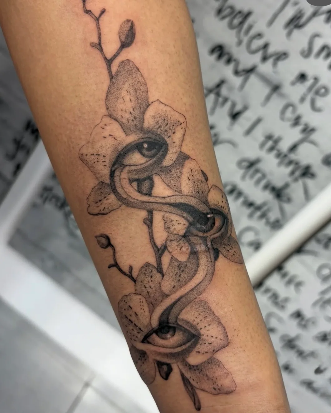 Fine line orchid and snake tattoo on the forearm by Livi Muir at SANS PATRIE/ STUDIO