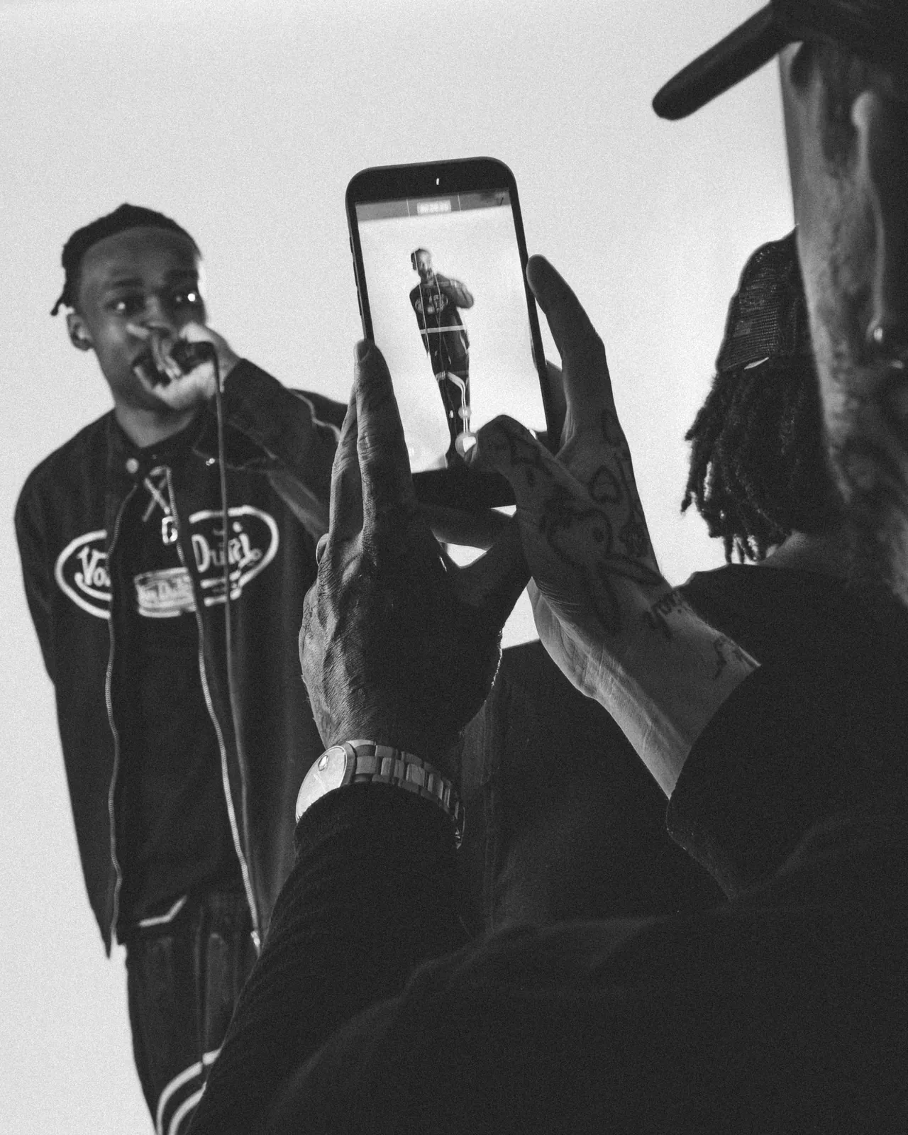 A guest photographs a performer in a Von Dutch jacket during the live shoot at the studio