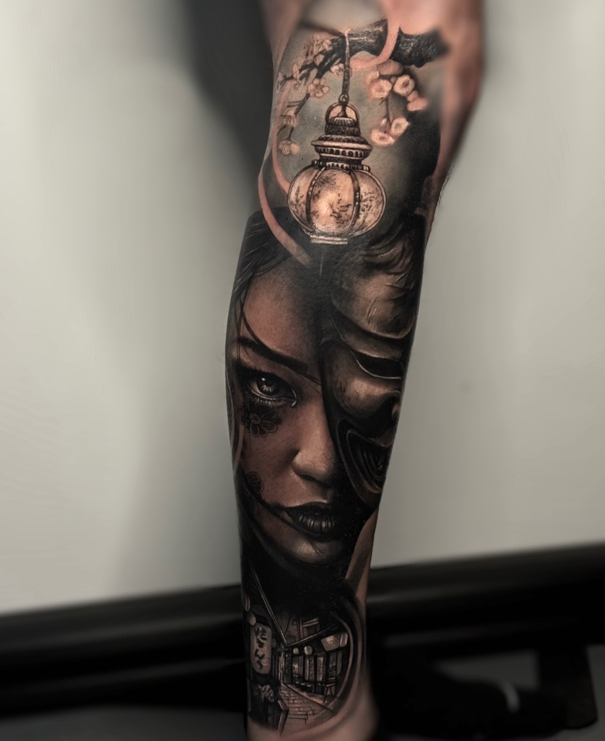Black and grey geisha with lantern and cherry blossom leg tattoo by Kayley Laroche at SANS PATRIE/ STUDIO