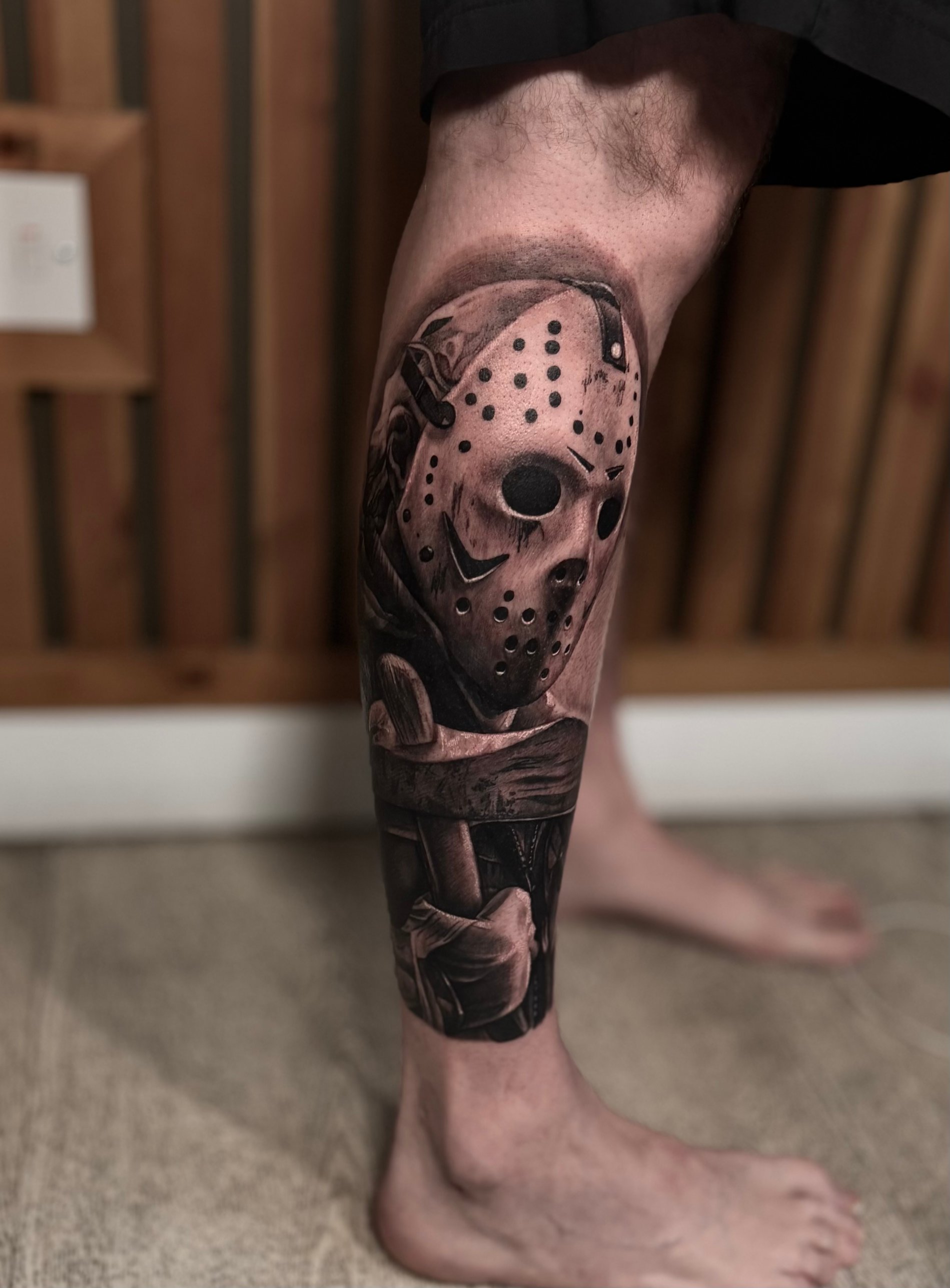Black and grey hockey-mask horror calf tattoo by Kayley Laroche at SANS PATRIE/ STUDIO