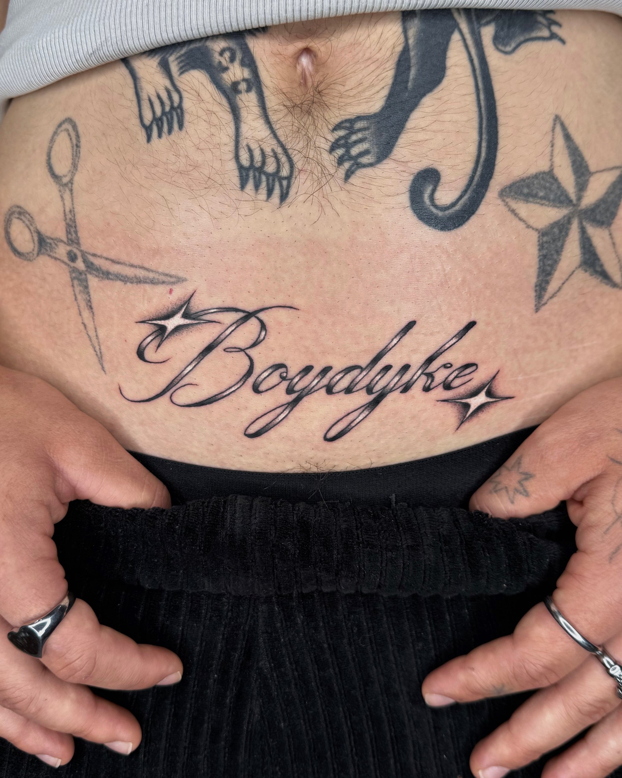 Script lettering stomach tattoo with sparkles by Tommy Burley at SANS PATRIE/ STUDIO