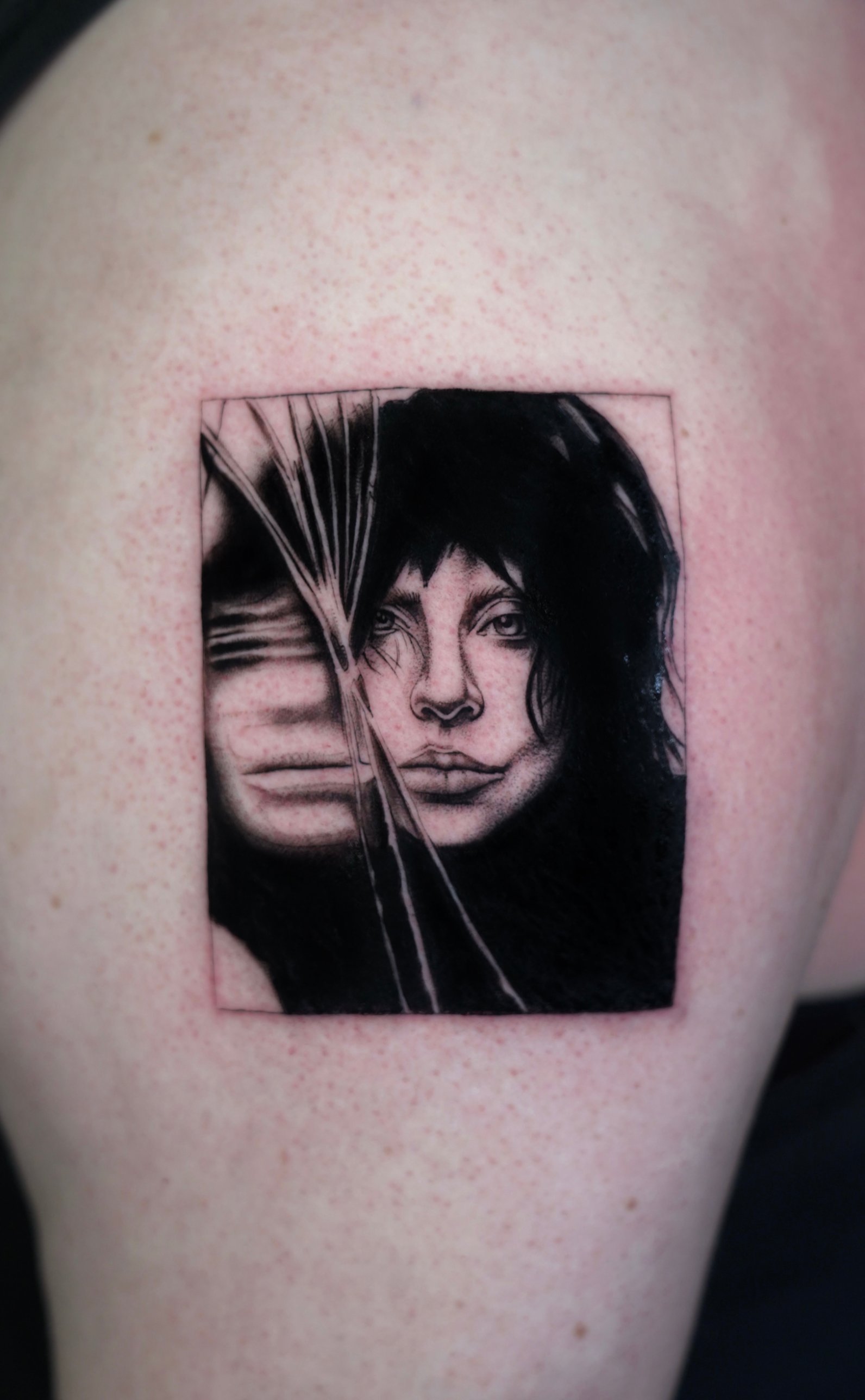 Framed blackwork portrait seen through shattered glass, thigh tattoo by Tommy Burley at SANS PATRIE/ STUDIO
