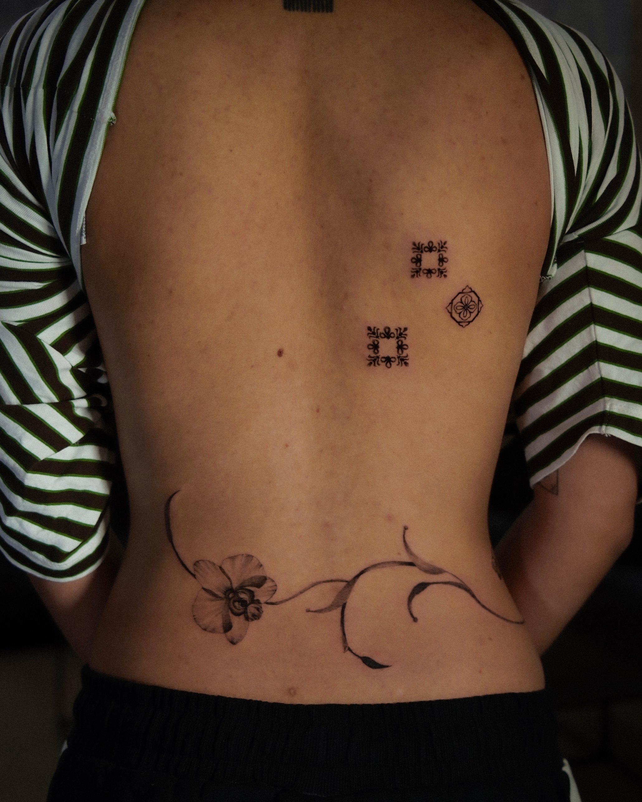 Ornamental tiles and fine line orchid vine back tattoo by Kimberley Verana at SANS PATRIE/ STUDIO