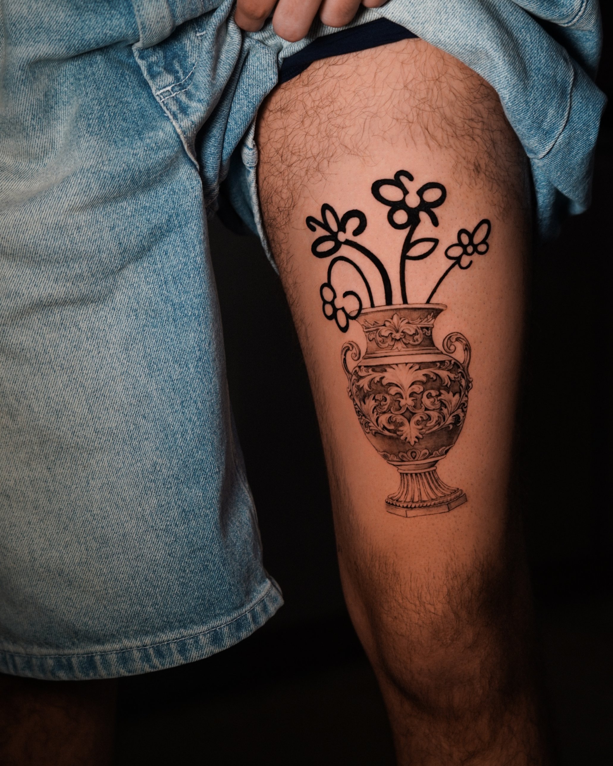 Micro-realism ornate vase with bold outline flowers thigh tattoo by Kimberley Verana at SANS PATRIE/ STUDIO