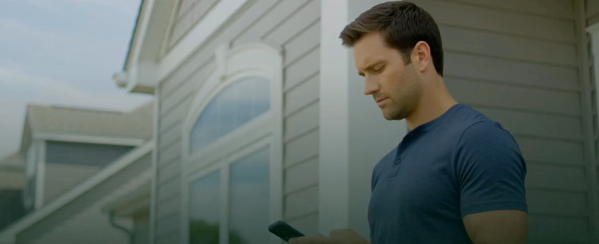 A homeowner checking a phone outside their house