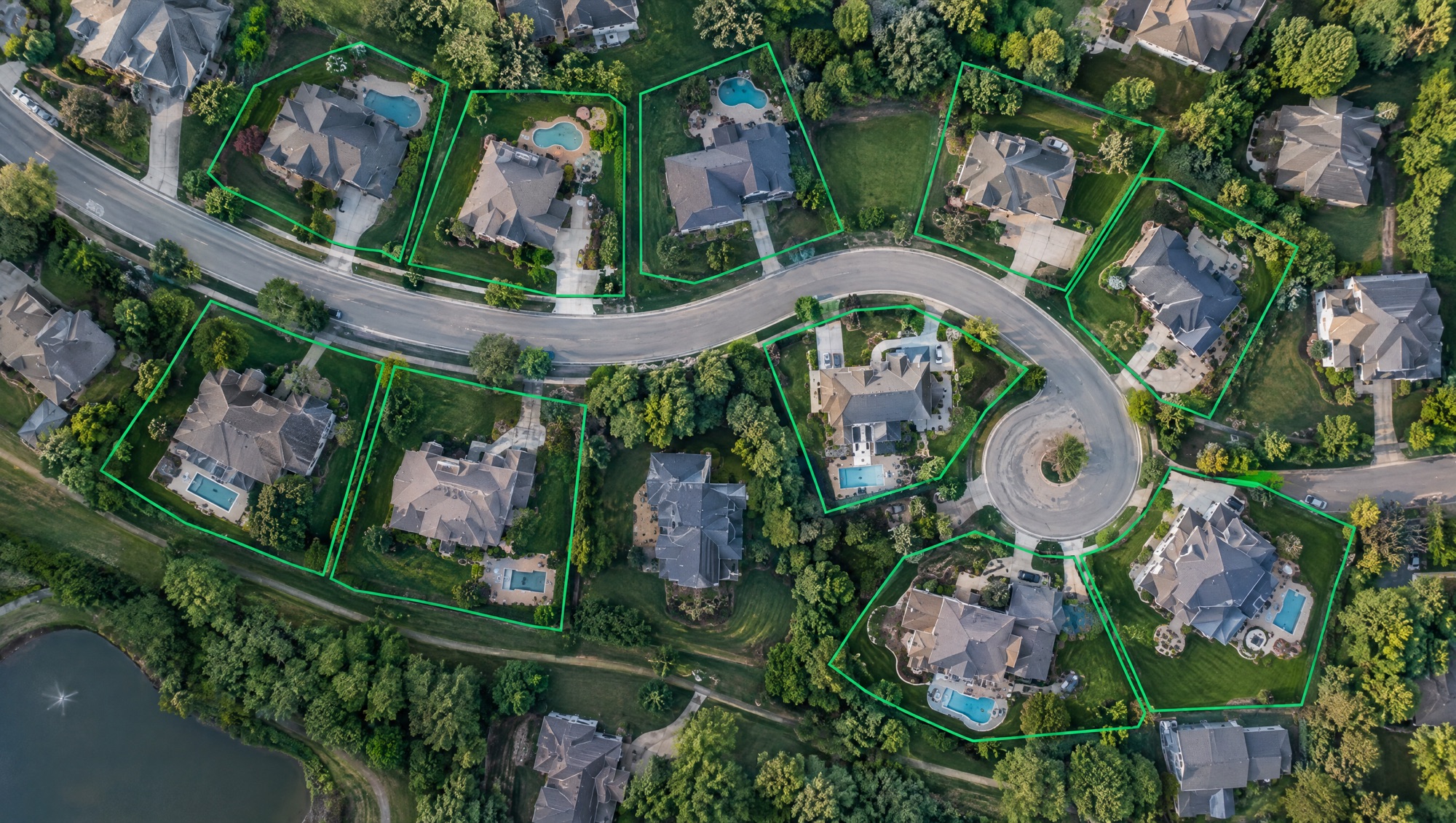 Aerial view of a suburban neighborhood with individual homes outlined by green geofences