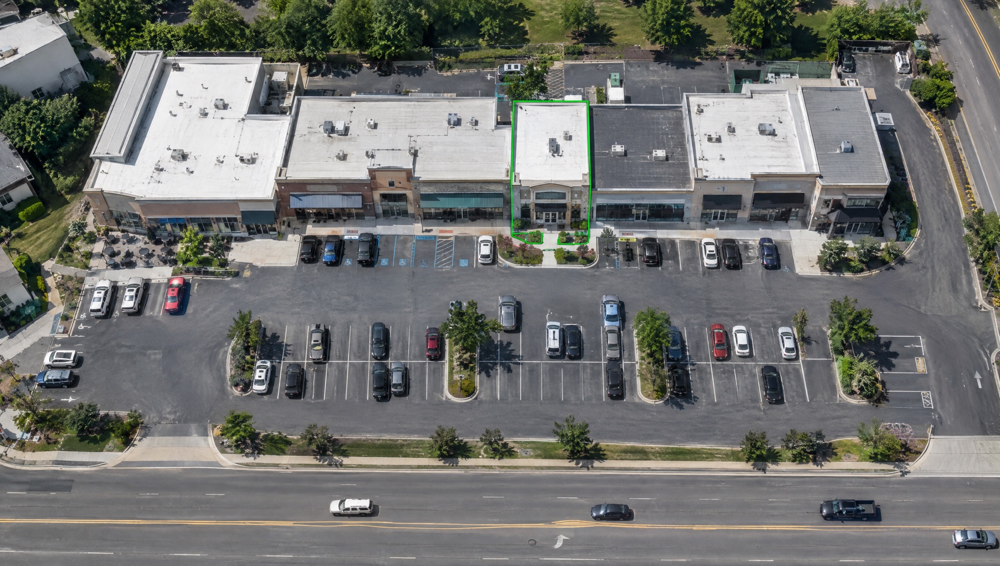 Aerial view of a retail strip with one storefront outlined by a green geofence