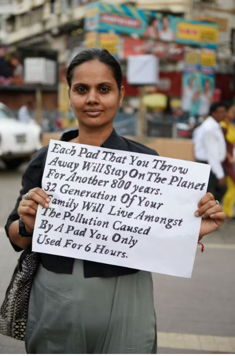 A woman in India holds a sign about eco-friendly menstrual cups