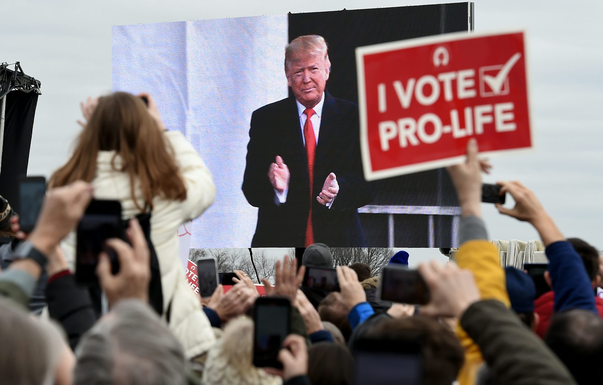 A crowd watches Donald Trump on a screen at the March for Life
