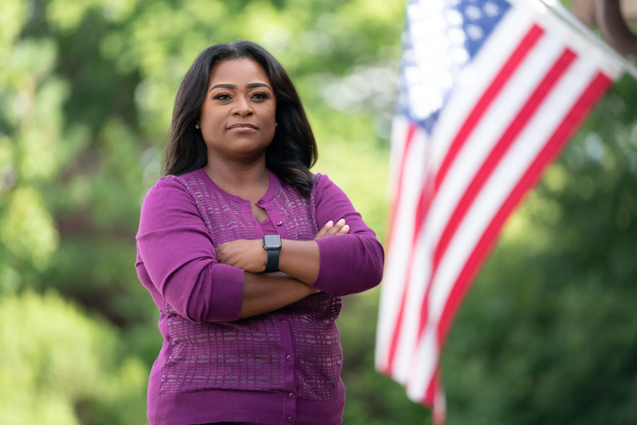 Diamond Staton-Williams stands with arms crossed in front of an American flag.