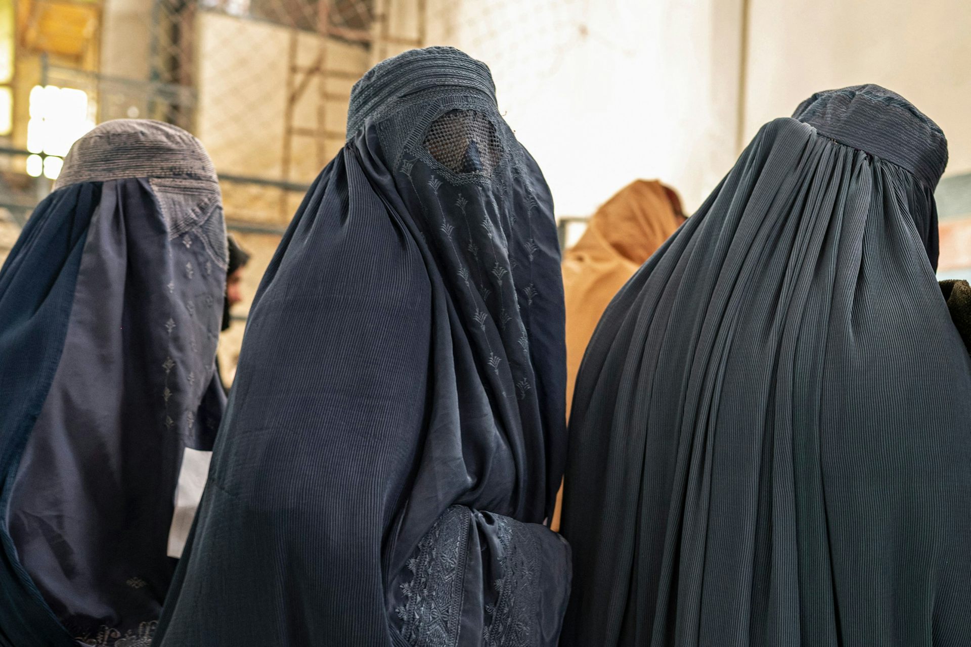 Women wearing blue burqas stand in a line