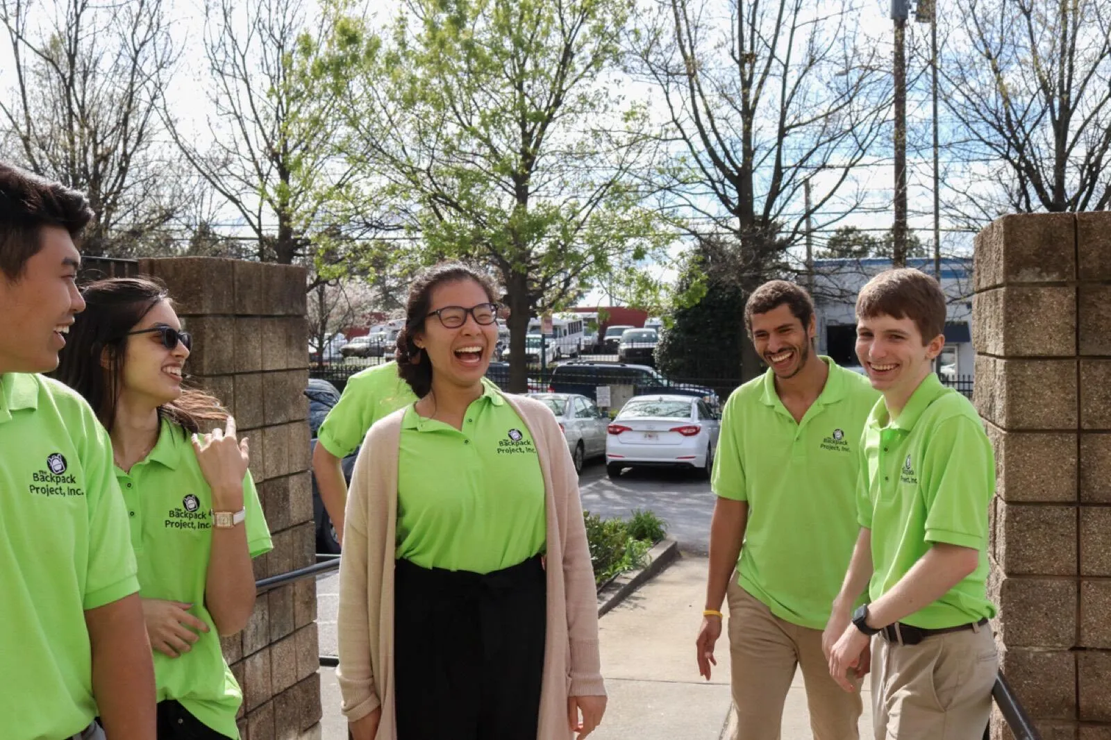 Volunteers in green polos laugh together before a distribution.