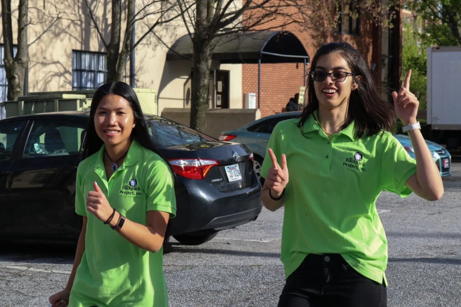 Two chapter volunteers in green polos smile on distribution day.