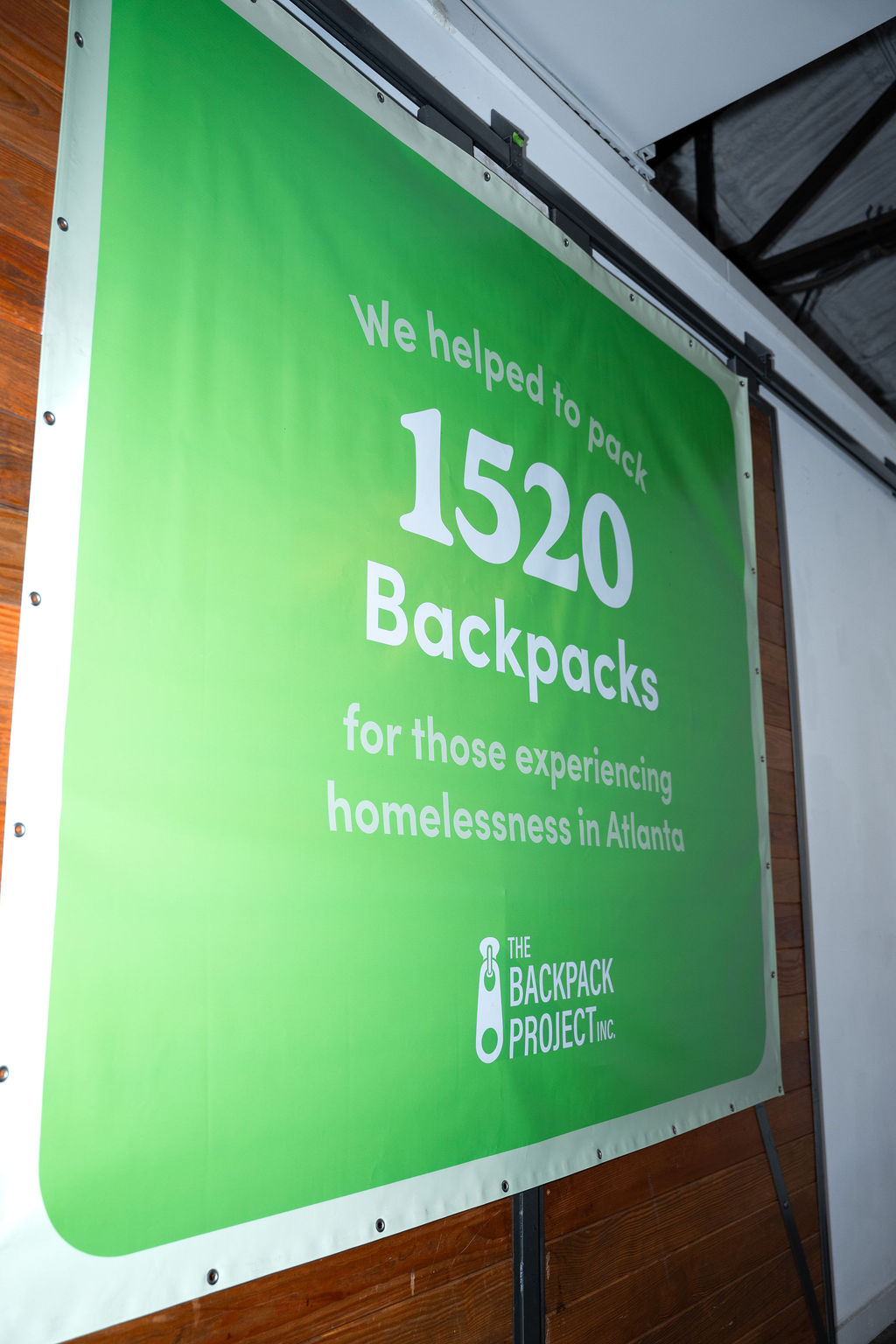 Banner at Homeless Heroes Day 2025 reading: We helped to pack 1520 backpacks.