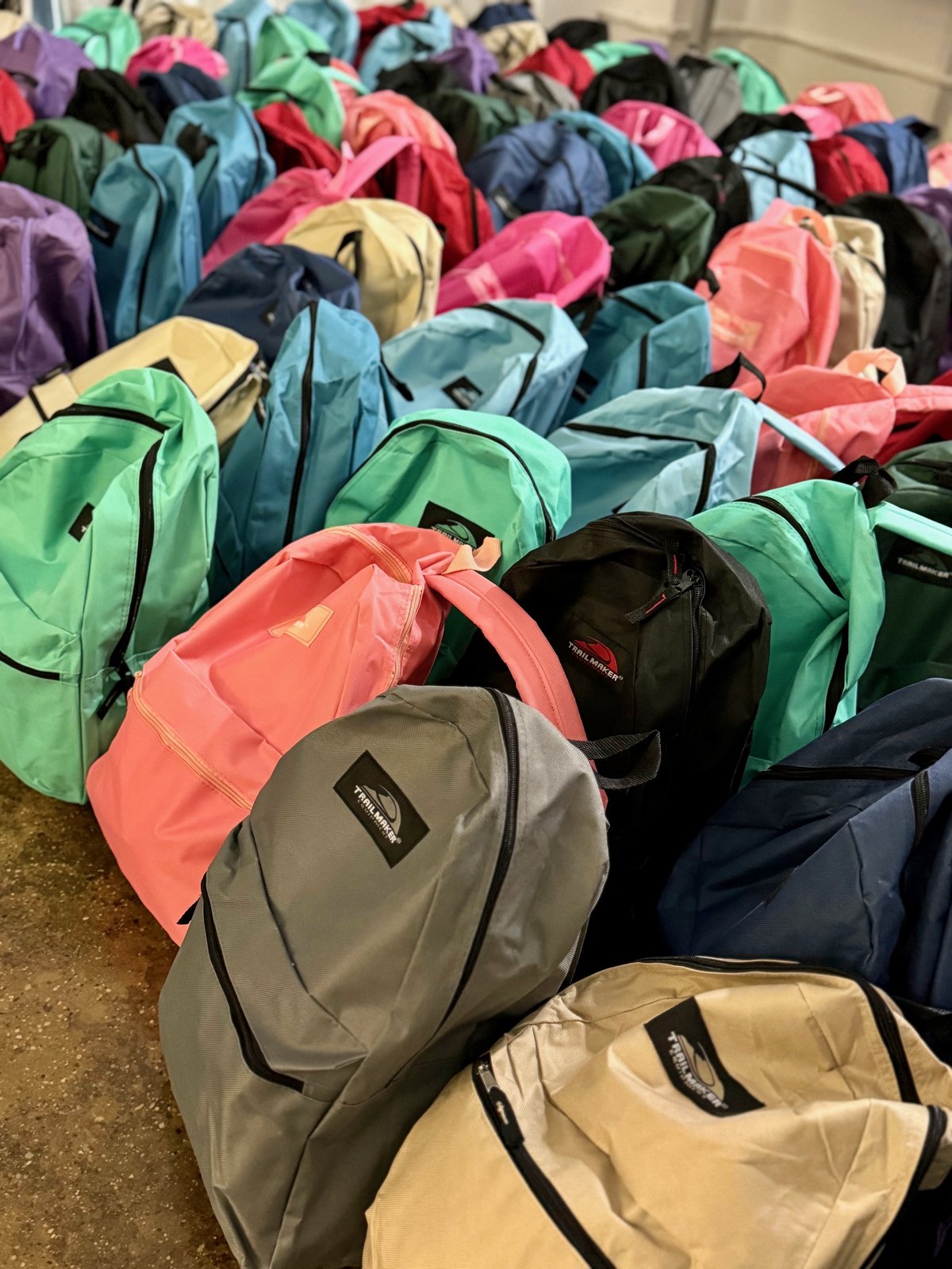 Rows of colorful packed backpacks on the floor after a Sharecare packing.