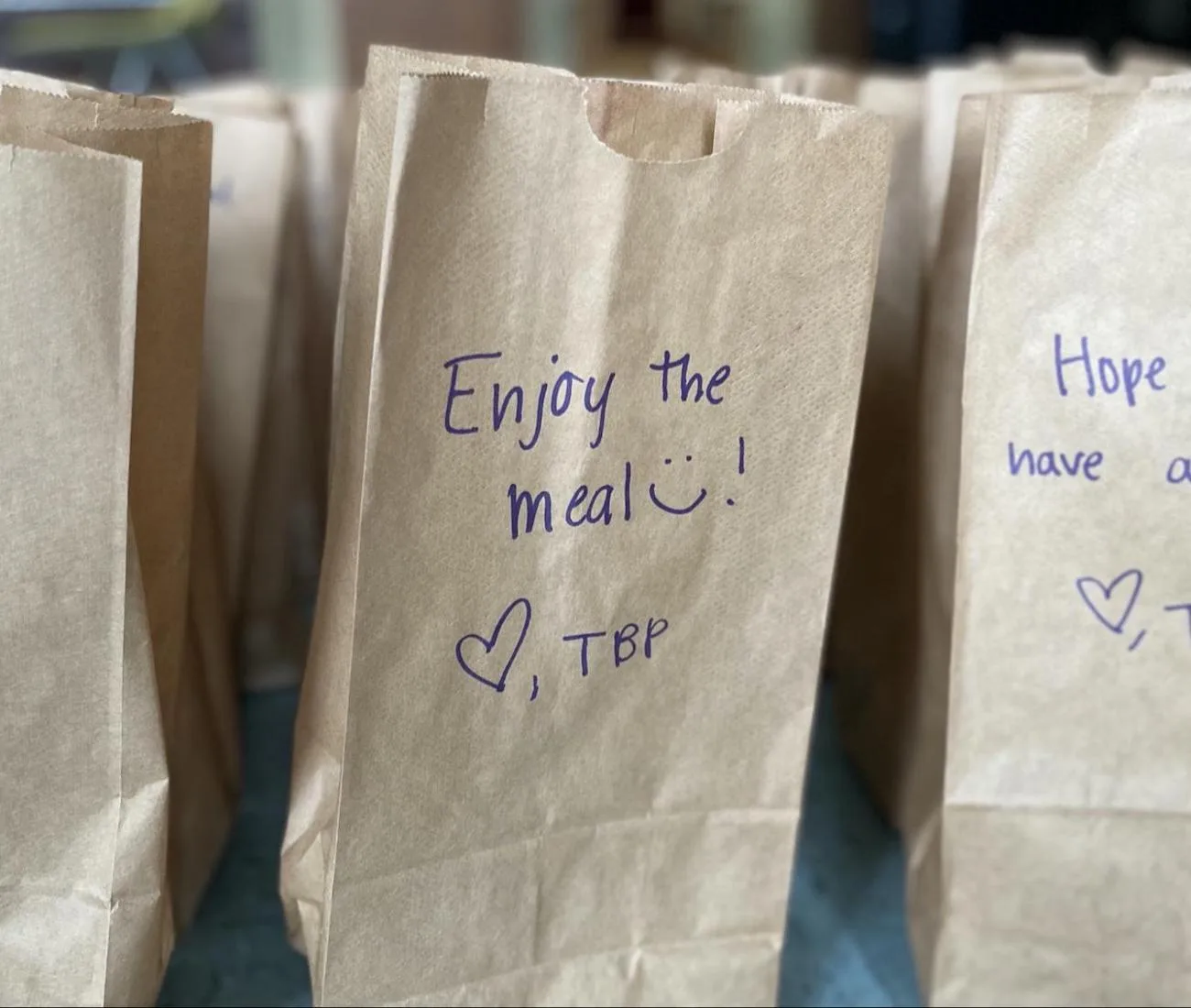 Brown paper meal bags with handwritten notes that say Enjoy the meal, from the Athens chapter.