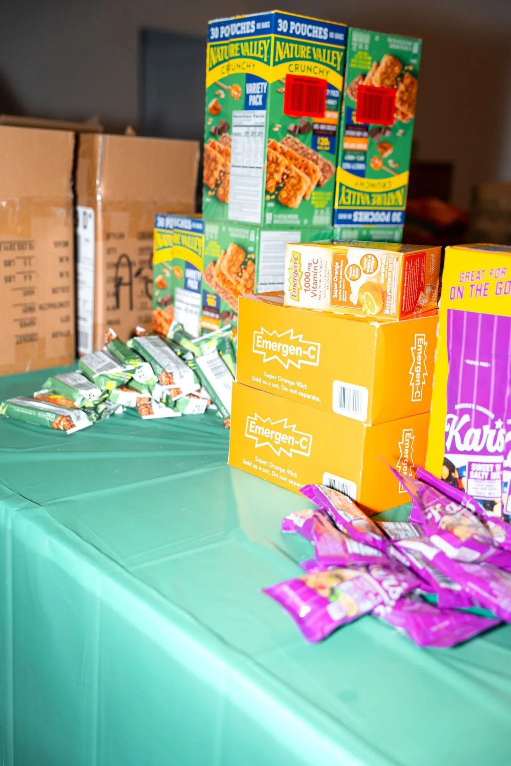 Granola bars, vitamin C packets, and trail mix staged on a packing table at Homeless Heroes Day 2025.