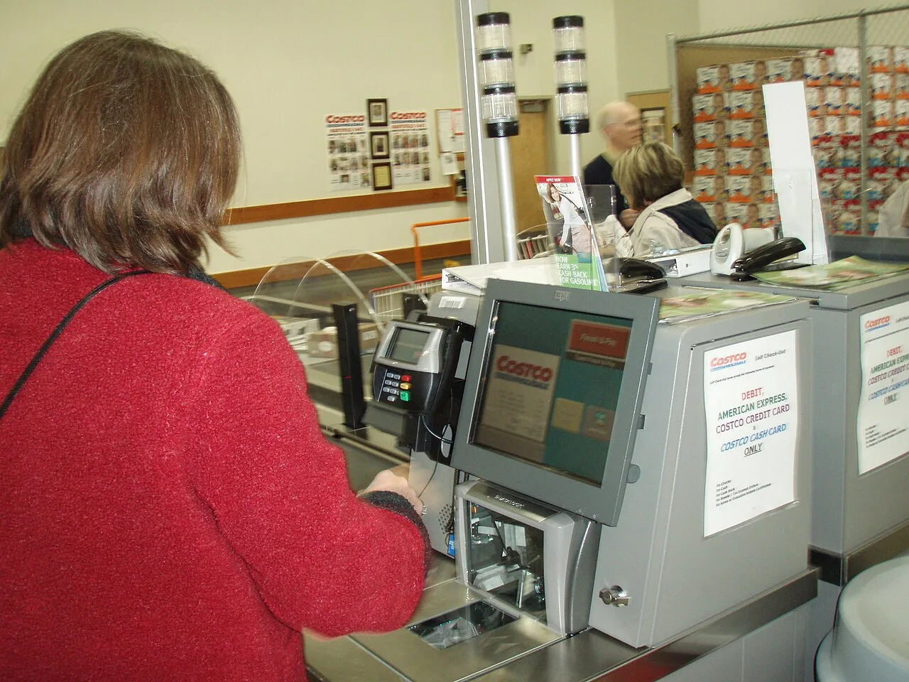 Person using a store checkout terminal with a touchscreen and card reader.
