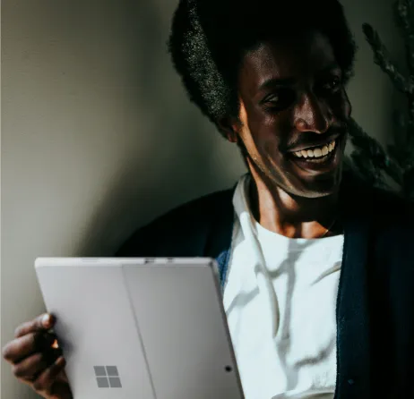 Smiling man using a tablet in a dim room