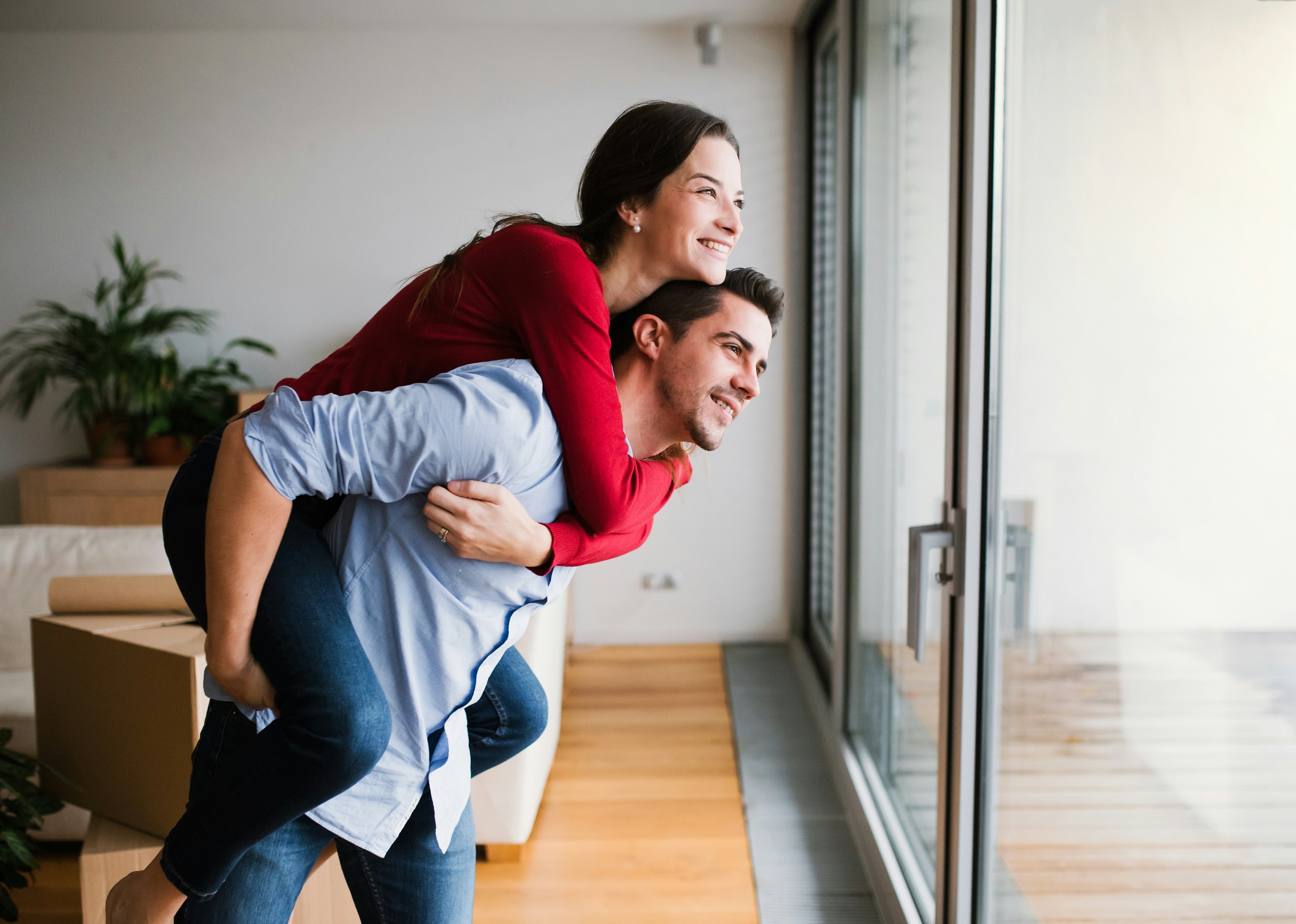 A smiling couple looking out the window of their new home