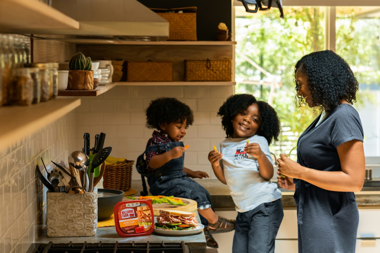 A mother with her two young children in the kitchen