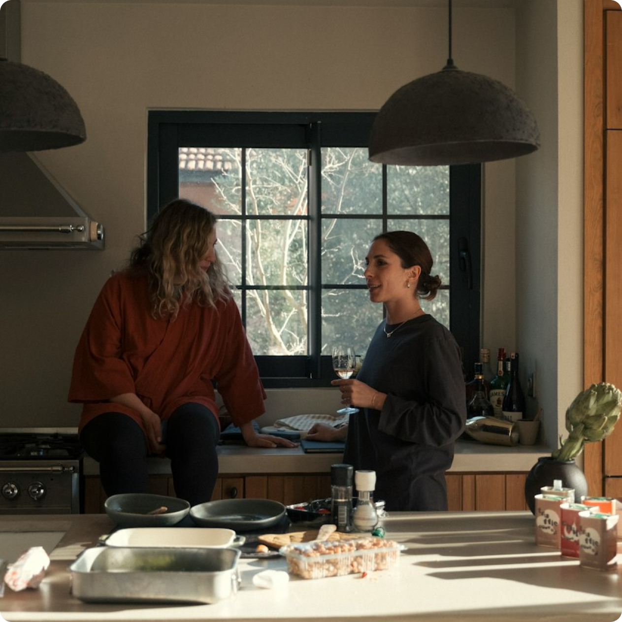 Two women talking in a warm, sunlit kitchen